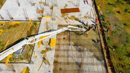 Above view rigger, worker is holding pump hose to pouring fresh concrete into building foundation...