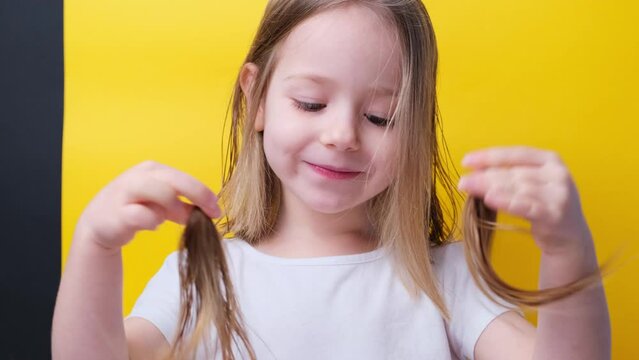 A funny little girl holds shake hands cropped hair two braids after hair cutting