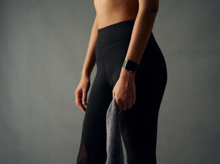Close-up of biracial young woman with fitness tracker wearing leggings and holding towel in studio - Powered by Adobe