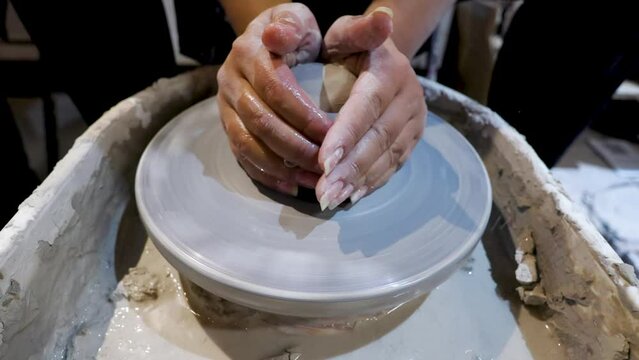 overhead close view of an African American hands spinning clay very sporadically while pushing the mold  from above