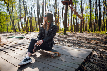 Fototapeta premium Woman sitting at forest with longboard at summer time