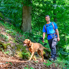 Wanderer mit Hund bei einer Erlebnistour am Jägersteig bei Dollnstein im Naturpark Altmühltal - obrazy, fototapety, plakaty