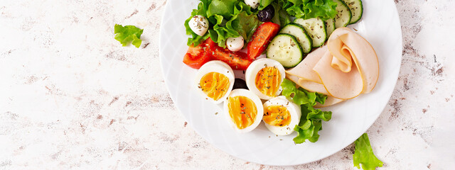 Ketogenic diet. Boiled eggs, ham, mozzarella cheese and fresh salad.  Keto breakfast. Brunch.  Top view, banner