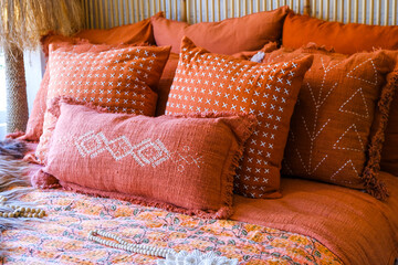 Closeup of headboard in bedroom in staging model home, house or apartment with decorative bright coral pillows