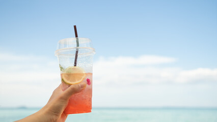 Hand Women holding Strawberry Iceland Sodap in Glass on blur Blue Sea and Sky,Tropical Summer Juice Fruit Drink,Cocktail Tourism Resort in Vacation Holidays,Snack on Food on Table at Coast.