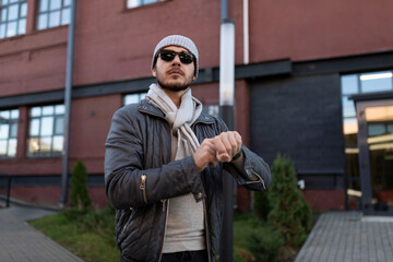 young stylish man in sunglasses looks into the distance checking the time on his watch