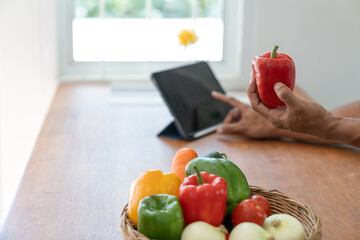 Healthy and strong Asian fit man wearing apron preparing vegetable baskets in kitchen at home before cooking online happily stay healthy and safe from disease.