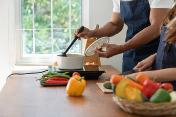 Young Asian couple in apron learning to choose ingredients Ingredients salad dressing in pot, suitable breakfast with salads, vegetables, fruits, available online. lifestyle healthy cooking concept