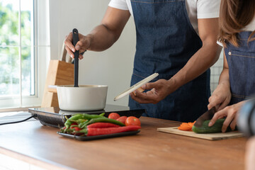 Young Asian couple in apron learning to choose ingredients Ingredients salad dressing in pot, suitable breakfast with salads, vegetables, fruits, available online. lifestyle healthy cooking concept
