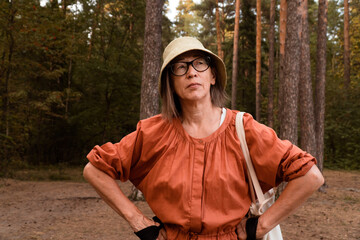 senior active healthy woman in hat and glasses at walk in forest