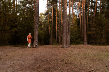 Fototapeta premium Unrecognisable woman in hat and linen wear at walk in forest