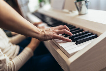 Child practicing on the modern electric piano at home. Music lesson. Close-up.