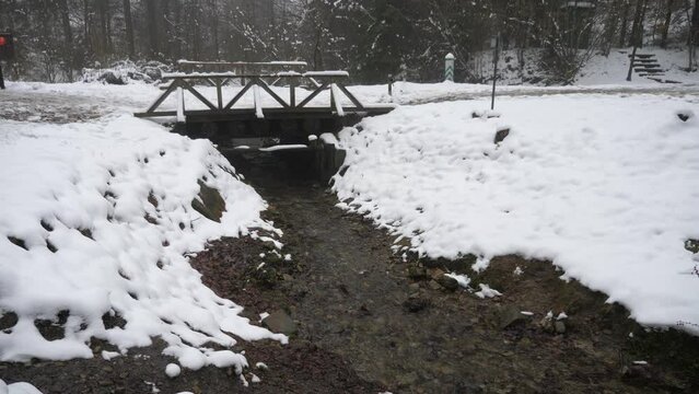 Winter landscape with an old footbridge over a small river, high in the mountains in winter