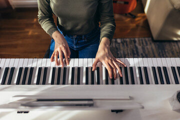 Child practicing on the modern electric piano at home. Music lesson. Close-up. High angle view.