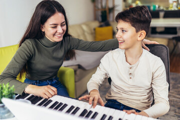 Fototapeta premium Brother and sister play electric piano at home and have fun.