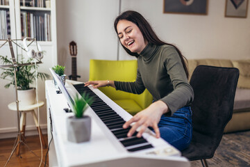 Happy girl is playing piano for her hobby relax time in home living room. Portrait Of Smiling Teenage Girl At Home Playing The Piano