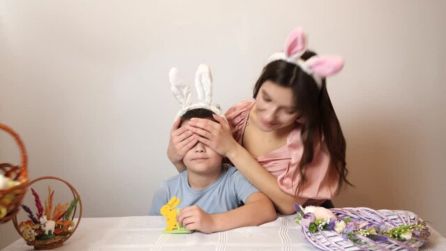 The girl closes her brother's eyes and makes a surprise for him. Celebration in the family. Easter games and fun.