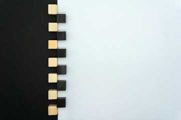 左右に別れた白が多めの白黒の背景の境界に交互に置かれたウッドキューブの正面
