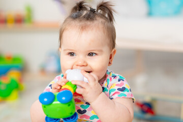 the baby nibbles toys, the child plays at home in the nursery. Toys for small children.
