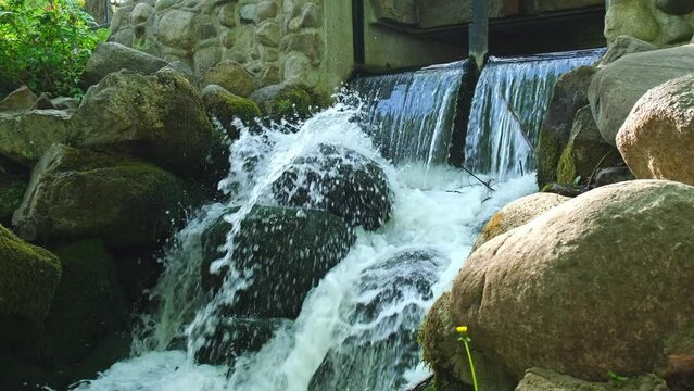 Waterfall cascade in Olivia public park Gdansk Poland. River waterfall falls from cliff and trees. Tourist attraction with small waterfall and clear water Unity with nature