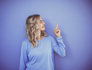 beautiful, sporty woman with blonde curls and purple top against purple background