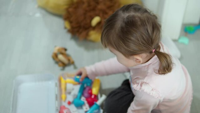 Age 3 Girl with Pigtails Playing Doctor Using Toy Plastic Tools to Check Examine Neck Tonsils