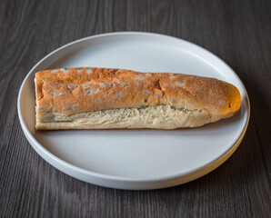 Moldy bread in a white ceramic plate on a wooden table, top view. Stale and wasted food. Spoiled...
