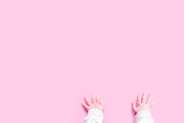 Baby hands crawling on a pink background top view