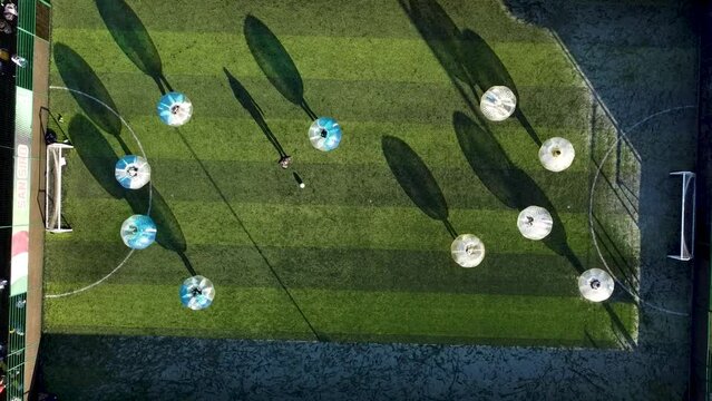 Aerial footage of Zorb football being played below at sunset. 