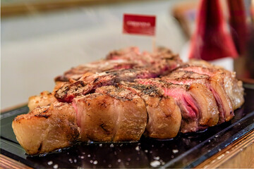 Classic seared dry aged T-bone Florentine steak from a Chianina cow steaming on a grill serving...