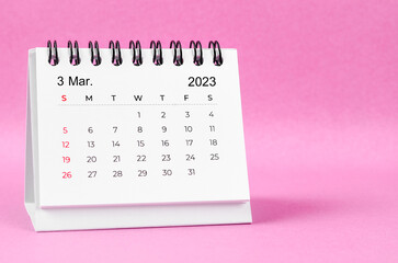 The March 2023 desk calendar on pink color background.
