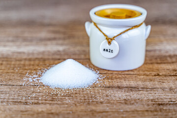 White salt spilled on a wooden table, selective focus.