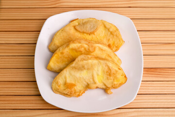 Fried breadfruit served on a white square plate on the table