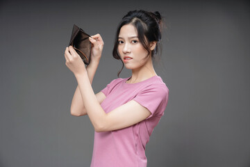 Young Asian woman holding empty wallet on background