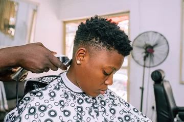 Foto op Plexiglas A young queer masculine woman getting a haircut © Ajay Abalaka