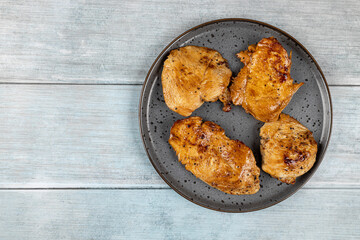 Chicken breasts barbecued and served on the blue plate above dark moody background