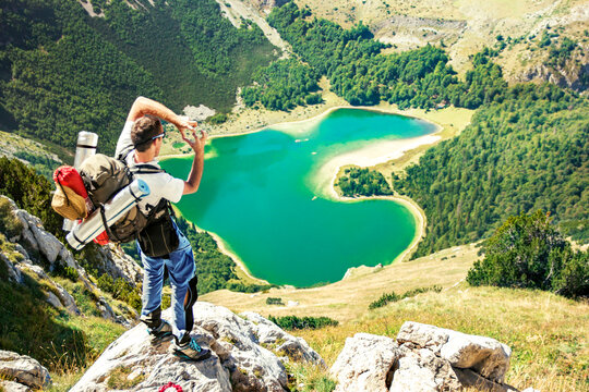 Hiker above heart shaped lake in mountains
