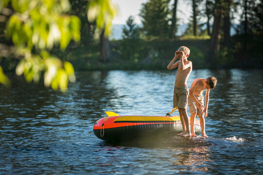 Two Boys swimming and playing on an inflatable raft in Duck Bay on Payette Lake in McCall, Idaho