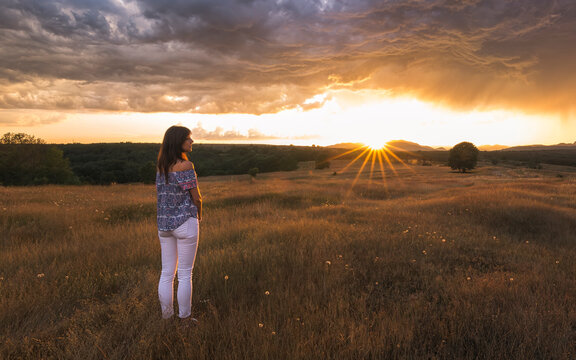 Woman observing some big clouds at sunset.