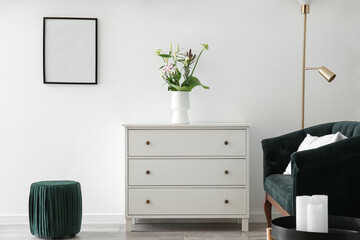 Interior of stylish living room with drawers, flowers in vase and pouf