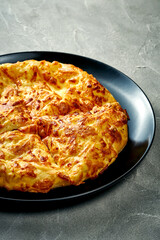 Khachapuri with salty melted cheese in a plate. Concrete background