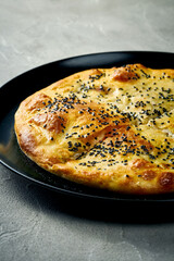 Khachapuri with salty melted cheese in a plate. Concrete background