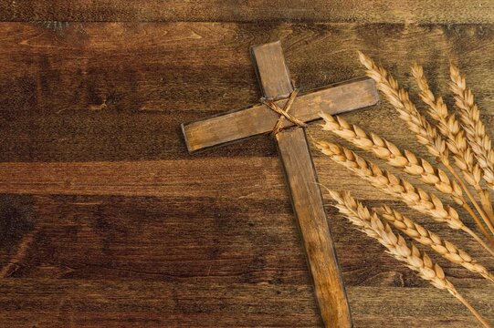 Wood cross and golden wheat on desk