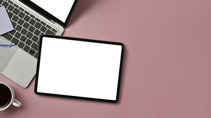 Top view of digital tablet, laptop, coffee cup and notepad on pink background. Copy space for text information or content