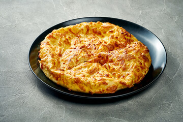 Khachapuri with salty melted cheese in a plate. Concrete background