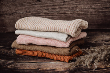 Fototapeta na wymiar The pile of knitted sweaters on dark brown background