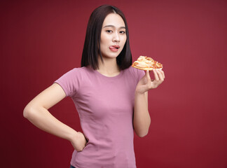 Young Asian woman eating pizza on background