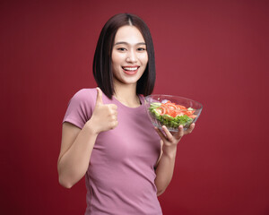 Young Asian woman eating salad on background