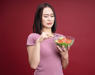 Young Asian woman eating salad on background