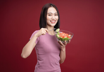 Young Asian woman eating salad on background